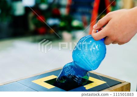 Close up hand throwing empty plastic water bottle into recycling bin, recycle rubbish 111501883