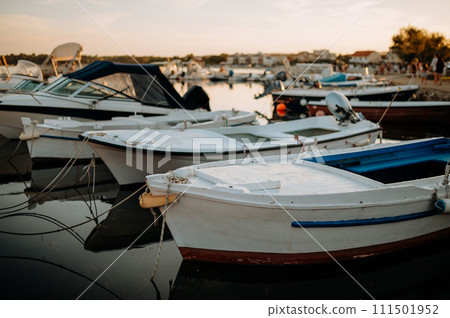 Small boats on calm water, moored in the harbor during sunset. 111501952