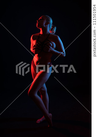 Seductive plump blonde woman in dark studio on dark background with neon lights Seductive plump blonde woman in dark studio on dark background with neon lights 111501954