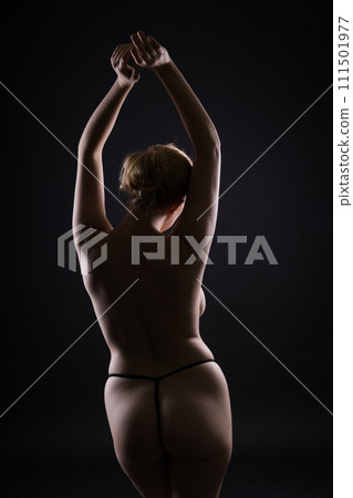 Seductive plump blonde woman in dark studio on dark background with neon lights 111501977