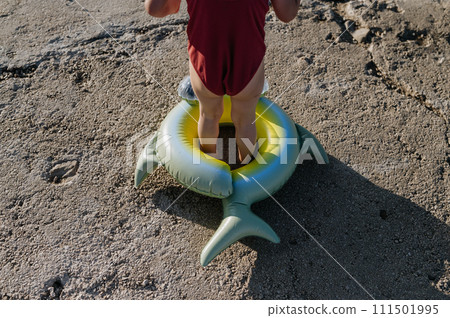 Close up of small girl standing inflatable toy ring, looking at sea. Close up of small girl standing inflatable toy ring, looking at sea. 111501995