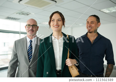Happy young female business leader in formalwear moving forwards with two intercultural male colleagues or subordinates Happy young female business leader in formalwear moving forwards with two intercultural male colleagues or subordinates 111502389