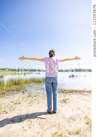 Woman with Outstretched Arms Embracing Nature 111503676