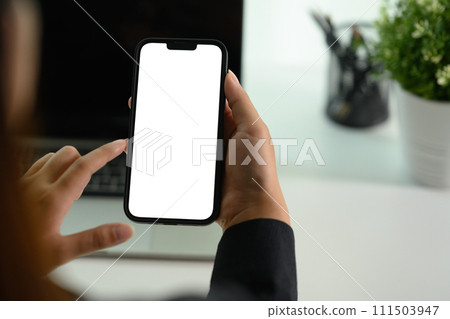 Female worker using mobile phone at her office desk. Closeup, blank screen for your advertising text. Female worker using mobile phone at her office desk. Closeup, blank screen for your advertising text. 111503947