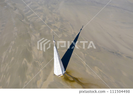 Aerial view of a church tower with cross, buried under mud and mining residuals 111504498