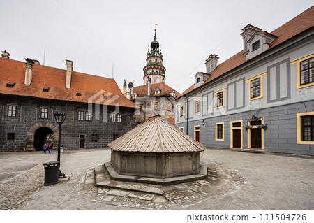 Empty courtyard with wooden fountain cover on foreground, castle buildings and tower on background, Cesky Krumlov, Czech Republic, Europe 111504726