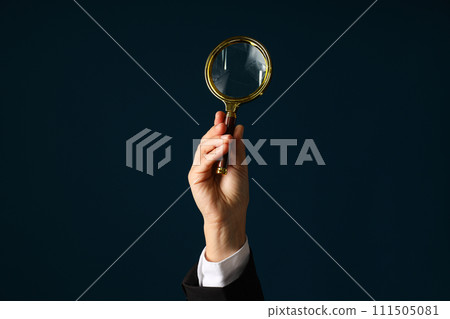 A businessman's hand holds a magnifying glass 111505081