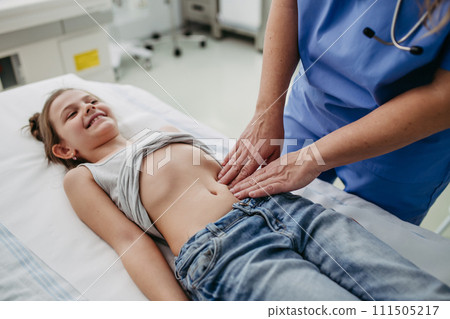 Close up of doctor palpating girl's abdomen, touching with hands and steady pressure on belly. Concept of preventive health care for children. Close up of doctor palpating girl's abdomen, touching with hands and steady pressure on belly. Concept of preventive health care for children. 111505217