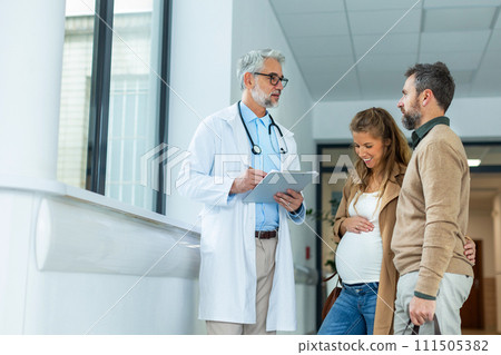 Pregnant woman and husband talking to obstetrician in hospital. Admitting woman in labor to maternity ward, planned cesarean section delivery. 111505382
