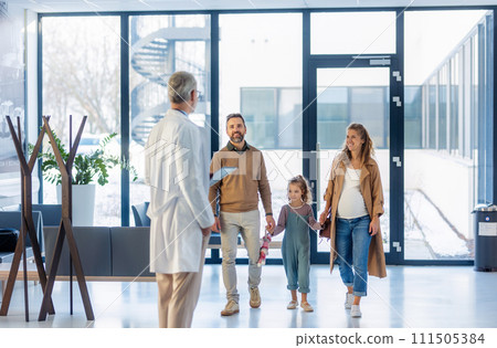 Girl patient looking forward to her doctor and examination in a modern clinic. Girl arriving in hospital with her parents. Emotional support during medical examination. 111505384