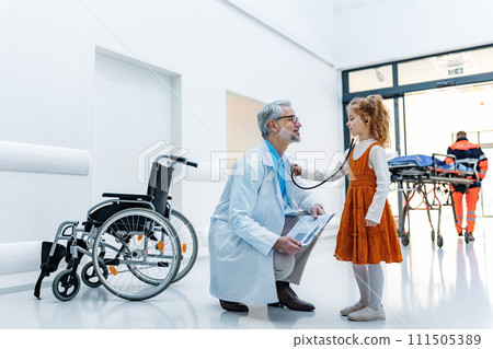 Little girl listening to the doctor's heart with stethoscope. Role reversal. Friendly relationship between the doctor and child patient. Little girl listening to the doctor's heart with stethoscope. Role reversal. Friendly relationship between the doctor and child patient. 111505389
