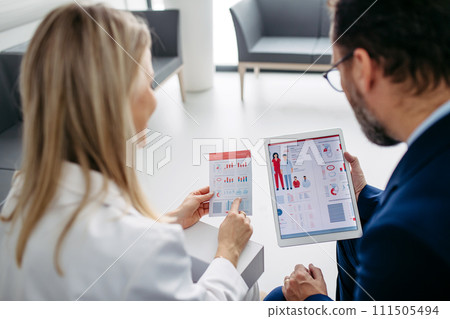 Rear view of pharmaceutical sales representative talking with doctor in medical building. Ambitious male sales representative presenting new medication. Rear view of pharmaceutical sales representative talking with doctor in medical building. Ambitious male sales representative presenting new medication. 111505494