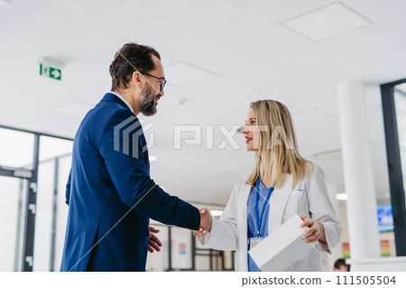 Pharmaceutical sales representative talking with doctor in medical building. Ambitious male sales representative presenting new medication on tablet. 111505504