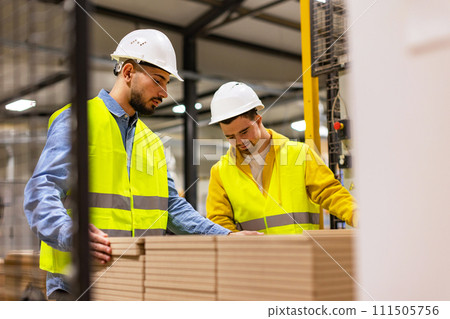 Young man with Down syndrome working in modern factory, colleague teaching him about his job, showing process. Concept of workers with disabilities, support in workplace. 111505756