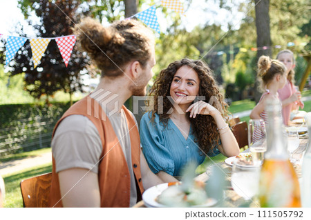 Portrait of couple sitting at the table with family and friends at the family garden party. Portrait of couple sitting at the table with family and friends at the family garden party. 111505792