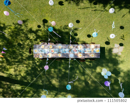 Top view of summer garden party in a beautiful garden. BBQ family gathering, with set table and colorful decorations. 111505802