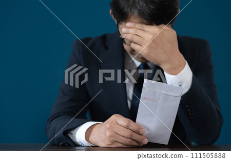 A worried businessman with a resignation letter in hand A worried businessman with a resignation letter in hand 111505888