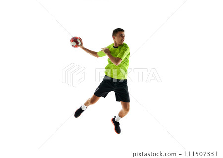 Competitive young guy in uniform, handball player in a jump, throwing ball during game against white studio background Competitive young guy in uniform, handball player in a jump, throwing ball during game against white studio background 111507331