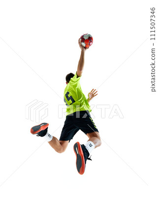 Dynamic back view image of young guy in uniform handball playing in motion, jumping with ball against white studio background Dynamic back view image of young guy in uniform handball playing in motion, jumping with ball against white studio background 111507346