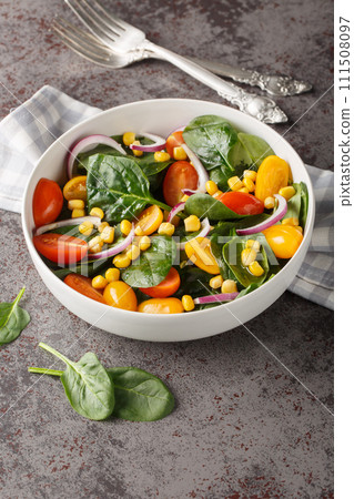 Fresh salad of spinach, corn, cherry tomatoes and onions dressed with olive oil close-up in a bowl. Vertical Fresh salad of spinach, corn, cherry tomatoes and onions dressed with olive oil close-up in a bowl. Vertical 111508097