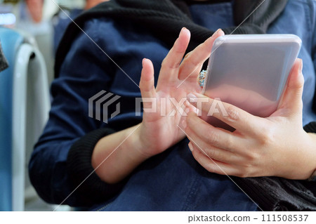 Close-up of a woman's hands holding and using a smartphone Close-up of a woman's hands holding and using a smartphone 111508537