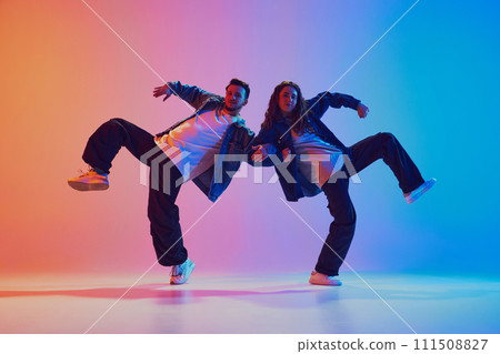 Dynamic portrait of dance duo, talented man and woman in dance poses against gradient studio background in neon light, filter. 111508827