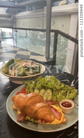 Croissant sandwich eaten at a cafe 111509949