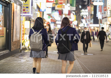 Rear view of a high school girl in uniform walking through Shibuya Center Street at night Rear view of a high school girl in uniform walking through Shibuya Center Street at night 111510513