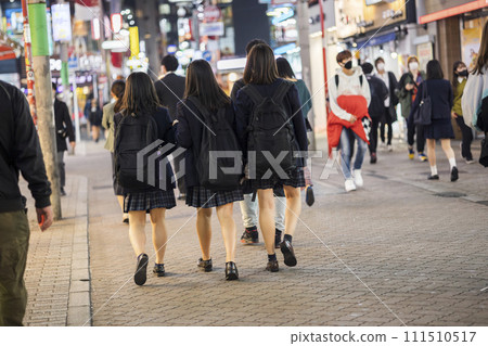 Rear view of a high school girl in uniform walking through Shibuya Center Street at night 111510517