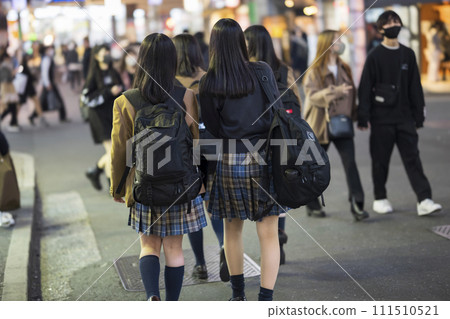Rear view of a high school girl in uniform walking through Shibuya Center Street at night 111510521