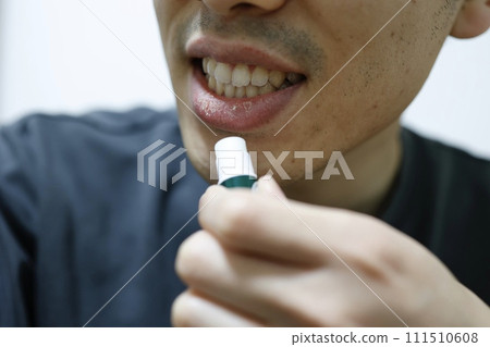 男人在乾燥的嘴唇上塗潤唇膏 男人在乾燥的嘴唇上塗潤唇膏 111510608