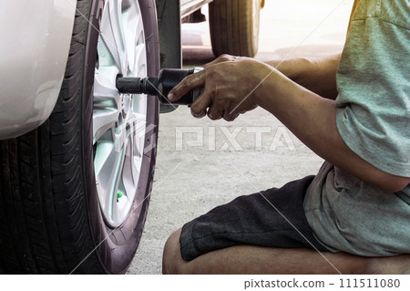 Car mechanic screwing or unscrewing car for change car tires at repair service station Car mechanic screwing or unscrewing car for change car tires at repair service station 111511080