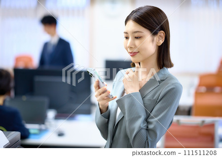 在辦公室使用智能手機的女商人 在辦公室使用智能手機的女商人 111511208