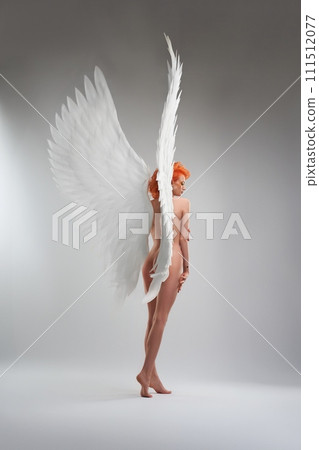 Naked woman with angel wings in light studio Naked woman with angel wings in light studio 111512077