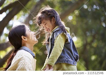 young asian mother talking to daughter outdoors in park young asian mother talking to daughter outdoors in park 111512546