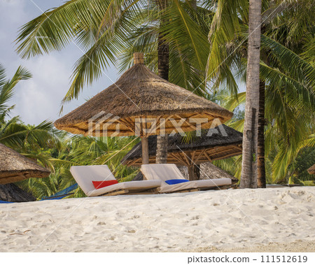 Nice wooden beach umbrella and luxury beach loungers on the beach at sunset 111512619