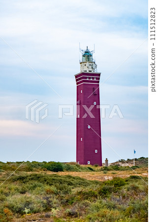 Majestic Red Lighthouse Standing Guard Over Coastal Dunes Majestic Red Lighthouse Standing Guard Over Coastal Dunes 111512823
