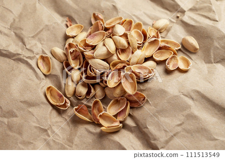 Separate waste collection concept. Organic biodegradable pistachio nushell on a recycled paper close up Separate waste collection concept. Organic biodegradable pistachio nushell on a recycled paper close up 111513549