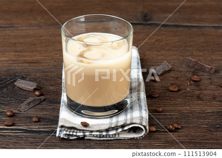 Glass with ice in original Irish cream liqueur, coffee beans and chocolate pieces. 111513904