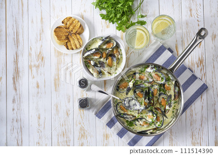Mussels in cream sauce with and toasted baguette on a wooden table copy space for text. 111514390