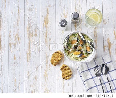 Creamy soup with seafood on a white wooden table, top view. 111514391