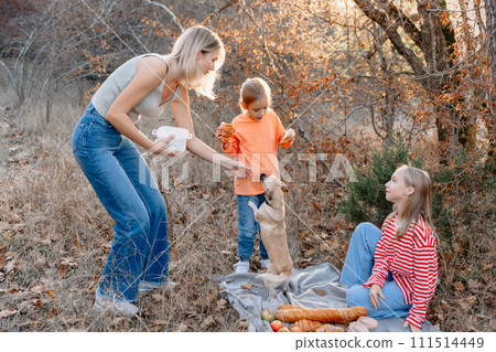 Mother with cute girls and dog relaxing on a picnic outdoor in forest 111514449