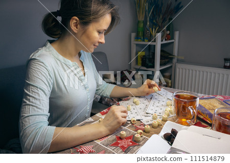 Girl playing in lotto with barrel in hand. Nostalgia lifestyle. Smiling woman playing bingo. Leisure activity. Retro table games. Luck concept. Positive emotions. Opportunity to win. 111514879