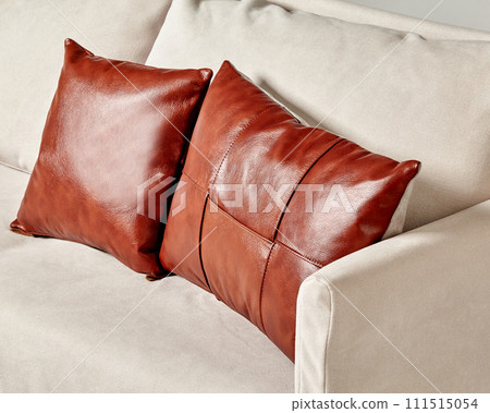 Brown leather pillows complementing modern light-grey sofa 111515054