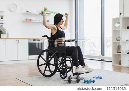 Caucasian woman in wheelchair stretching bands while exercising. Caucasian woman in wheelchair stretching bands while exercising. 111515083