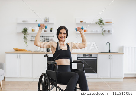 Caucasian person with disability holding dumbbells in raised arms. Caucasian person with disability holding dumbbells in raised arms. 111515095