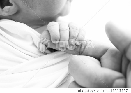Close-up of baby's small hand, head, ear and palm of mother. Macro. Black and white Photo of Newborn baby after birth tightly holding parents finger. Family and home concept. Healthcare, paediatrics Close-up of baby's small hand, head, ear and palm of mother. Macro. Black and white Photo of Newborn baby after birth tightly holding parents finger. Family and home concept. Healthcare, paediatrics 111515357