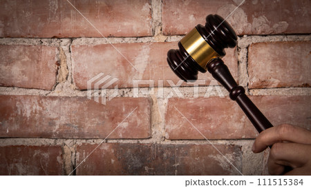 Judge hand holding gavel. Red brick background 111515384