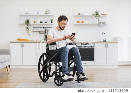 Male with disability texting message on phone in dining room 111515899
