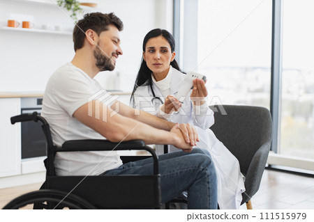 Woman doctor or nurse, visiting her mature male patient with disability at home. Woman doctor or nurse, visiting her mature male patient with disability at home. 111515979